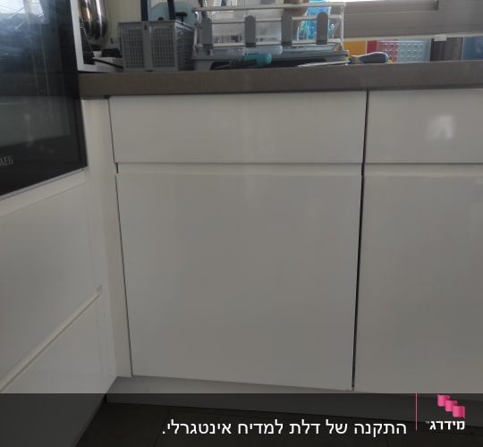 מטבח עם ארונות לבנים וכלי מטבח על השיש